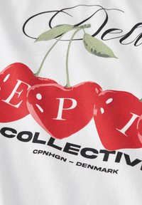Vitt tyg med en grafisk design som har röda körsbärsformer, svart text som säger "COLLECTIVE" och "CPNHGN - DANMARK" med fet stil.