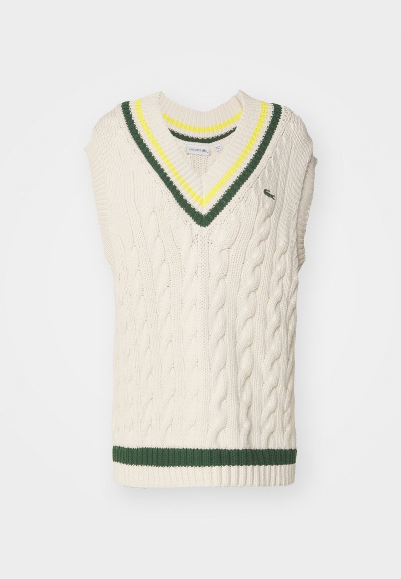 Pull sans manches en tricot torsadé crème avec un col en V. Présente un col ribbé à rayures vertes et jaunes et un ourlet ribbé vert. Logo Lacoste sur la poitrine.