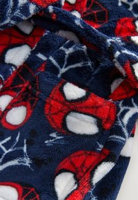 Fleece-heitoliina laivastonsinisellä pohjalla, jossa on punaisia, valkoisia ja mustia Hämähäkkimies-kuvioita. Pehmeä pinta, jossa on verkkomuotoilu ja suuria hahmomotiiveja.