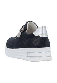 Baskets en daim bleu marine avec des accents métalliques argentés, fermeture éclair sur le côté, semelle plateforme blanche et détails texturés sur la zone des orteils.