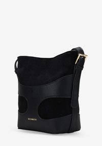 Bolso de mano negro que presenta una mezcla de texturas de cuero y ante, forma redondeada, correa ajustable y detalles en metal dorado.