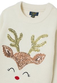 Cremfarbener Pullover mit geripptem Ausschnitt. Mit einem glitzernden Rentiergesicht, einer roségoldenen Schnauze und grünen Geweihen, sowie gestickten Augen und Nase.