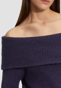 Schulterfreier Pullover aus dunkellila Rippstrickstoff, mit einem breiten, umgeschlagenen Kragen und einer weichen Textur.