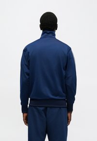 Μπλε ναυτικό φούτερ με ψηλό γιακά, με λεία υφή, ελαστικά μανίκια και αντίθετες ρίγες στα πλάγια.