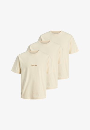 Trzy beżowe T-shirty z krótkim rękawem i okrągłym dekoltem, jeden z małym brązowym napisem „Originals Studio” na piersi, wyświetlone obok siebie.