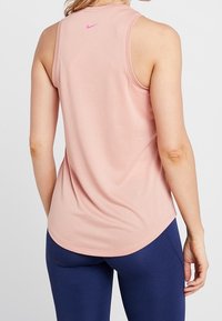 Hellrosa ärmelloses Sporttop aus weichem Stoff, mit abgerundetem Saum, sportlichem Schnitt und kleinem pinken Logo auf der Rückseite.