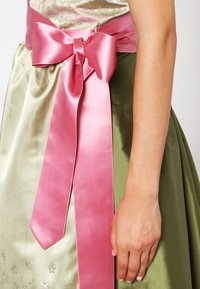 Vihreä satiini mekko, jossa on istuva yläosa ja luisuva hame, sekä leveä vaaleanpunainen satiinivyö vyötäröllä, solmittuna klassiseen solmuun.