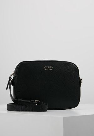 Sort tekstureret rektangulær skuldertaske med justerbar rem, sølv lynlås og "GUESS EST 1981" logo på fronten.