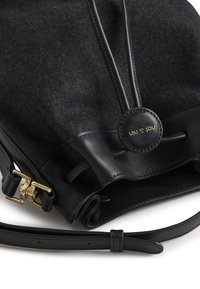 Borsa a tracolla in feltro nero e pelle, caratterizzata da accessori in oro, un accento con logo rotondo e una chiusura a coulisse con cinghie regolabili.