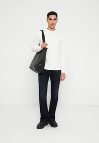 Maglione bianco a maniche lunghe, jeans blu scuro e borsa a tracolla in pelle nera. Scarpe nere completano l'outfit. Design semplice e moderno.