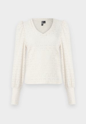 Vit stickad topp med V-hals, långa puffärmar och diamantmönstrad textur. Ribbstickade muddar vid ärmsluten. Mjuk, lätt tyg.