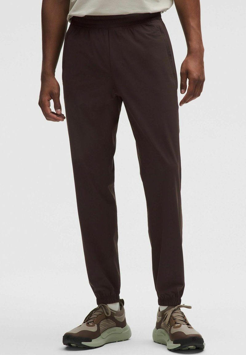 Braune, leichte Jogginghosen mit einem elastischen Bund und schmal zulaufenden Beinen. Tragen Sie dazu strukturierte Sneakers in neutralen Farbtönen.