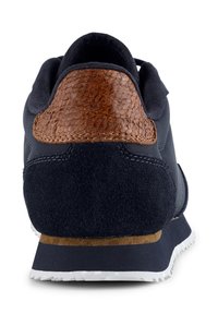 Tengerészeti stílusú sneaker, texturált barna bőr sarkú akcentussal, velúrból készült anyaggal, és feh�ér gumitalpéval, amely mintás taposófelülettel rendelkezik.
