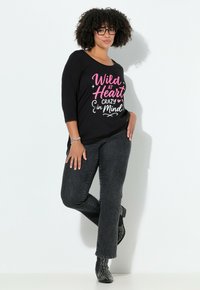 Černá košile s tříčtvrtečními rukávy s bílým a růžovým potiskem. Kombinována s tmavě šedými džínami a černými kotníkovými botami s nýty.