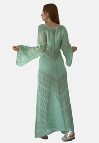 Długa, jasnoszara sukienka z geometrycznym, otwartym wzorem dzianiny i rozszerzanymi rękawami; zaprojektowana w dopasowanej sylwetce z zamkiem błyskawicznym z tyłu.