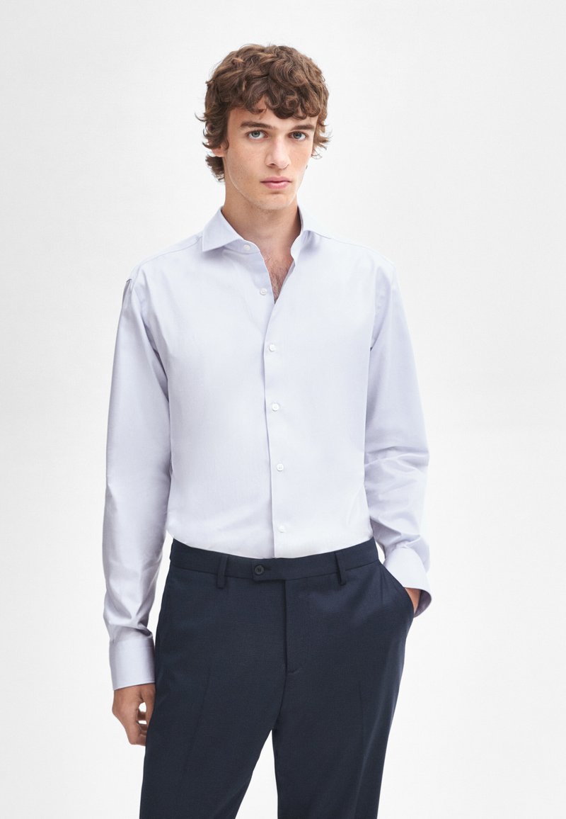 Lichtblauw overhemd met lange mouwen, een gestructureerde kraag en een gladde textuur, gecombineerd met donkere broek.