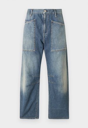 Denimjeans i lys til mellemblå, med store forlommer, en afslappet pasform og diskret falmen langs lårene og underbenene.
