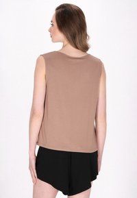 Top marrone senza maniche con scollatura rotonda, abbinato a pantaloni corti neri. Tessuto morbido con una vestibilità comoda.