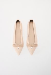 Ballerines beiges matelassées avec un bout pointu, ornées d'un accent nœud et d'un détail en perles sur une sangle texturée. Doublure intérieure lisse.