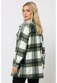 Zielono-biała flanelowa koszula w kratę z luźnym krojem, zapinana na guziki, z podwiniętymi rękawami, wykonana z miękkiego, teksturowanego materiału.
