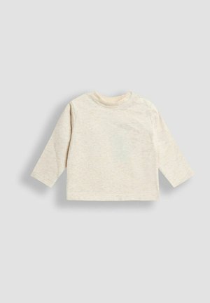 Vaaleanbeige pitkähihaisessa paidassa on pehmeä, tekstuuri kangas, pyöreä pääntie ja kaksi nepparia olkapäällä, mikä helpottaa pukemista.