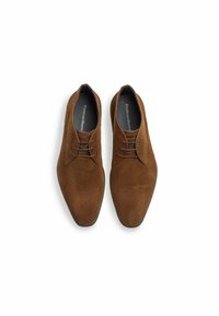 Chaussures en daim marron avec une texture lisse, une forme de bout pointu et des coutures subtiles. Elles présentent des lacets marron assortis et une semelle foncée.