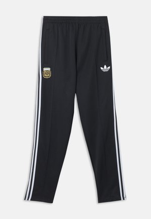 Pantalon de survêtement noir Adidas avec bandes blanches sur les côtés, taille élastique, écusson de l'Association de Football d'Argentine sur la cuisse gauche et logo Adidas sur la cuisse droite.