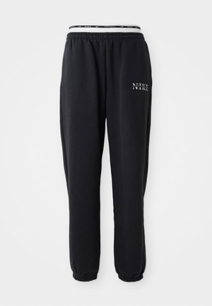Pantaloni della tuta neri realizzati in tessuto morbido con vita e polsini elasticizzati; presentano il logo bianco "NIKE" sulla coscia sinistra.