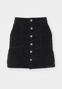 Jupe en velours côtelé noir à taille haute, avec une fermeture à boutons sur le devant équipée de boutons en métal argenté et deux poches latérales. Texture lisse.