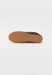Schwarzer Schuh mit strukturiertem Obermaterial, robustem schwarzen Material und brauner Gummisohle mit glatter Oberfläche. Das Design ist leicht und schlicht.