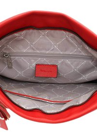 Intérieur d'un sac à main en cuir rouge avec une doublure grise à motif losange, une poche zippée et une poche plate. Souligné par un bord rouge.