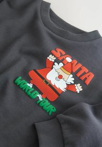 Szara bluza z kolorową grafiką Świętego Mikołaja, z wypukłym czerwonym napisem "SANTA" oraz zielonym napisem "WORLD TOUR" poniżej. Miękka tekstura, ryflowany dekolt.