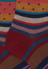 Multicolored socks featuring bold stripes and polka dots; materials include soft fabric with ribbed texture; predominant colors are reds, blues, and yellow.