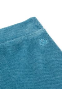 Tela de rizo azul con una textura acanalada. Presenta un acento de logo bordado cerca del borde superior. Material suave y esponjoso.