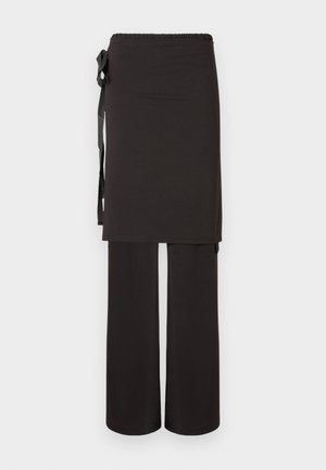 Schwarzes Zweiteiliges Outfit mit einem langen Oberteil mit elastischem Bund und Wickeldetail, kombiniert mit weitem Hosenbein. Glatte Textur.