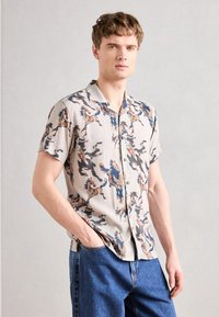Short-sleeve, light beige shirt with a multicolored abstract horse pattern; features a classic collar and buttons down the front.