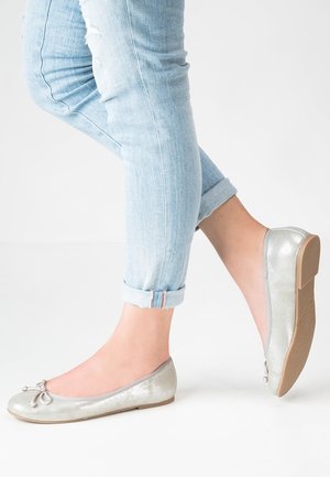 Zilveren, platte ballerina's met een gestructureerde afwerking en strikdetail op de teen. Gedragen met lichtblauwe, opgerolde spijkerbroek.