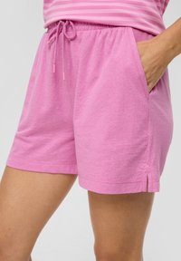 Rosa Baumwollshorts mit elastischem Bund, verstellbarem Kordelzug, seitlichen Taschen und kleinen seitlichen Schlitzen am Saum. Weicher Stoff.