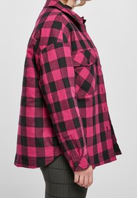 Camisa de franela a cuadros en rosa y negro con botones en la parte delantera, un bolsillo en el pecho y mangas largas, que presenta un ajuste relajado y material de mezcla de algodón.