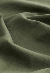 Olivgrüner Stoff mit weicher, glatter Textur und leichtem Stretch. Das Material hat ein gleichmäßiges Muster und einen dezenten Glanz.