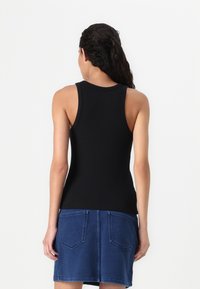 Zwarte, getailleerde tanktop met een ronde halslijn en brede bandjes, gecombineerd met een blauwe denimrok met een achterzakdetail.