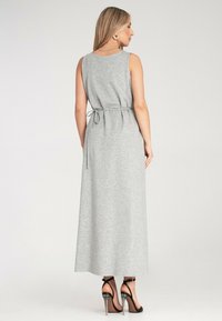 Szara, bezrękawna maxi sukienka z paskiem w talii i gładką fakturą. Zakończona prostym krojem, w zestawieniu z sandałami na obcasie w kolorze czarnym.