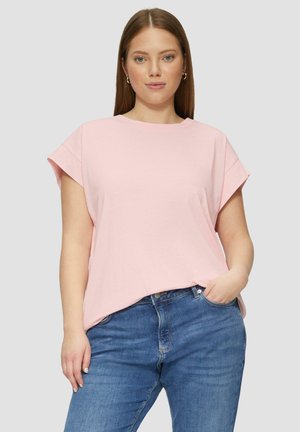 Lichtroze t-shirt met korte mouwen, een ontspannen pasvorm, ronde halslijn en zachte stof; gecombineerd met blauwe jeans.