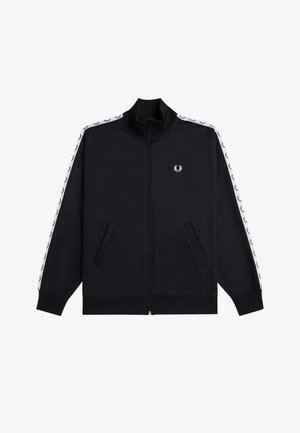 Chaqueta deportiva negra con logo de laurel blanco en el pecho, franja blanca con patrón repetido de laureles negros a lo largo de las mangas, cremallera frontal y bolsillos laterales.