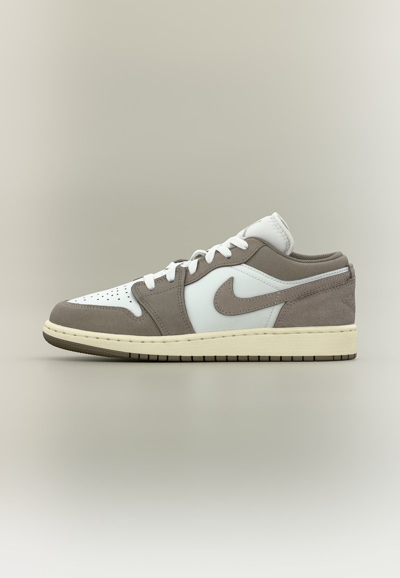 Χαμηλό sneaker με λευκό δέρμα και γκρι πάνελ σουέτ, λευκά κορδόνια, ανοιχτό μπεζ μεσαία σόλα και το λογότυπο Nike σε ουδέτερο φόντο.