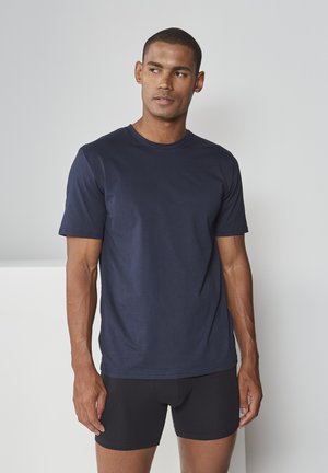 Navy blue short-sleeve t-shirt made of soft fabric, featuring a round neckline and a relaxed fit. Worn with black fitted boxer shorts.
