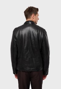 Black leather jacket with a smooth texture, featuring a classic collar, zippered cuffs, and seam detailing along the back and sleeves.