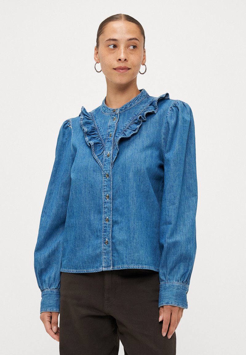 Denim-bluus, millel on volangkrae, pikad puffvarrukad ja nööbid. Helesinine värv, sile tekstuur ja peened fades detailid.