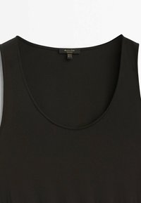 Haut noir sans manches avec un col rond et des bords cousus, affichant une petite étiquette de marque à l'intérieur du col.