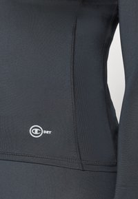 Zwarte sportieve langemouwen shirt van gladde stof met platte naden. Het heeft een klein wit logo met de tekst "DRY" aan de linkerkant.